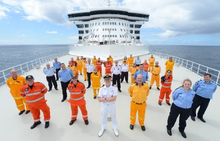 Australian emergency services volunteers with Cunard Commodore Christopher Rynd on the bow of Queen Mary 2 en route during their special voyage from Brisbane to Sydney